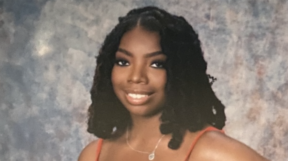 Portrait of Loyola University Chicago student with shoulder-length twists, smiling against studio backdrop